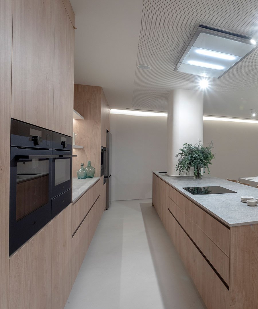 Detalle de la cocina del apartamento: hornos integrados, estanterías de madera y cerámica.