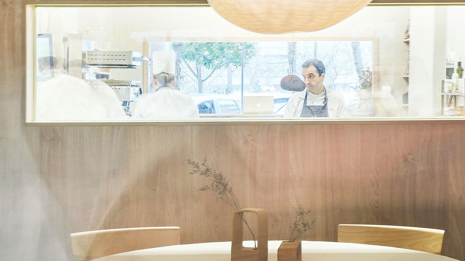 Óscar Velasco en el pase de la cocina, visto desde la sala a través de la ventana.