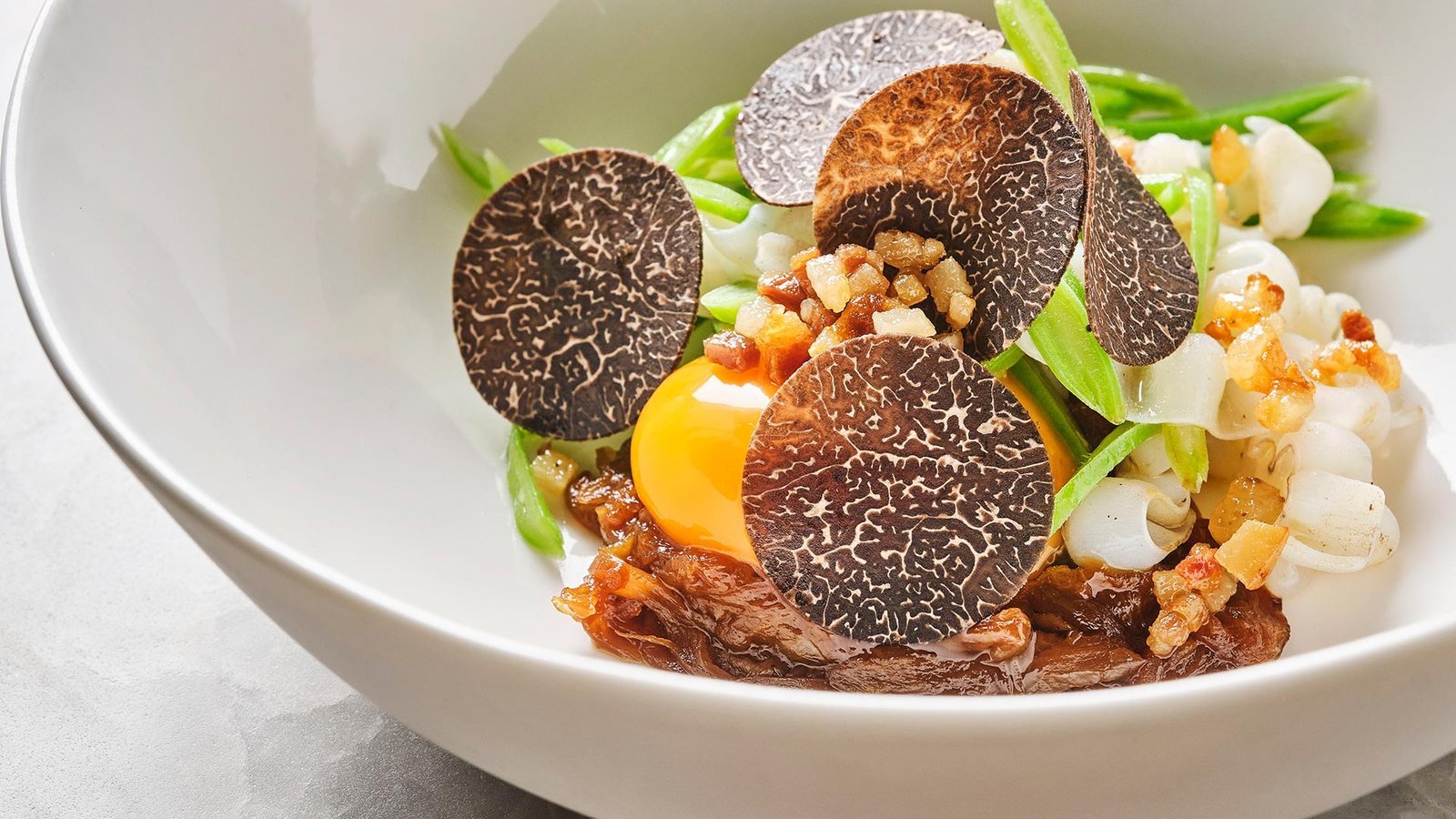 Plato con trufa negra laminada, yema de huevo y carrillera en su jugo.